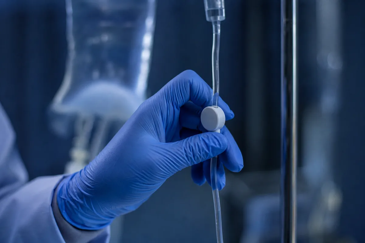 Main gantée d&rsquo;un soignant ajustant une ligne de perfusion dans une clinique vétérinaire